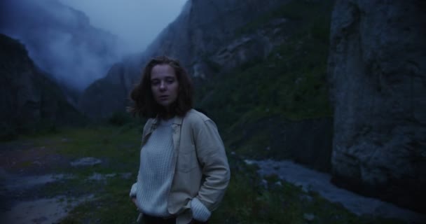 Кавказ, Эльбрус. Молодая женщина смотрит вокруг, стоя среди скалистых гор — стоковое видео