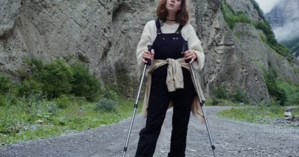 Elbrus. Jonge vrouw staat op de berg weg met stokken voor sport wandelen — Stockvideo