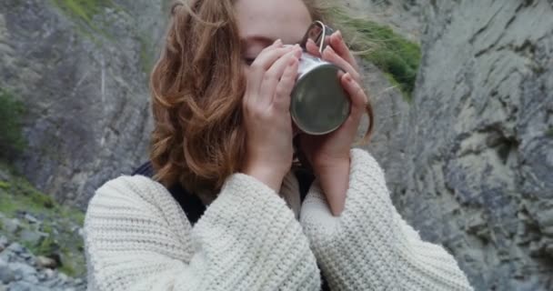Elbrus 。一个女孩站在山河边的岩石中喝酒 — 图库视频影像