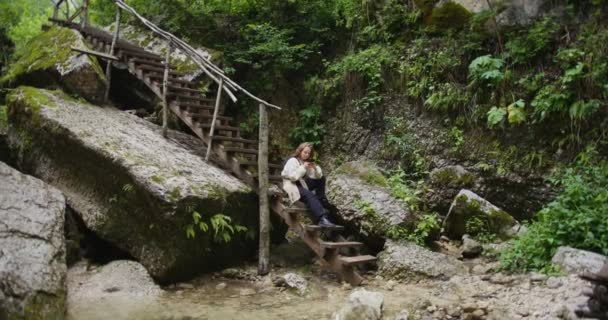 Oroszország, Kaukázus. Egy nő telefont használ, ami a sziklák között ül a lépcsőn. — Stock videók