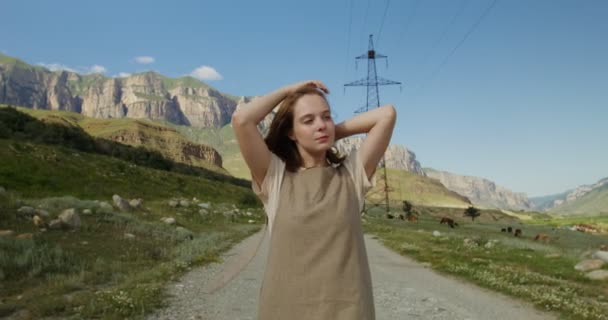 A Kaukázus.Fiatal nő sétál az úton a tehenek legelője, a hegyek között — Stock videók