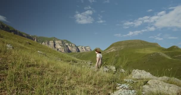 Rússia, Cáucaso. Uma mulher lentamente sobe colinas em direção a picos de montanhas — Vídeo de Stock