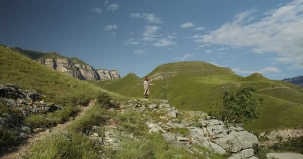 Rusya, Kafkasya. Bir kadın dağların zirvelerine doğru yavaşça tırmanıyor. — Stok video