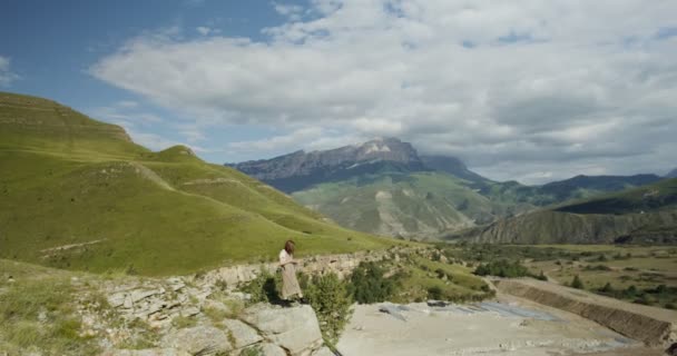 Rosja, Kaukaz. Młoda kobieta stoi na wzgórzu i patrzy na prace budowlane — Wideo stockowe