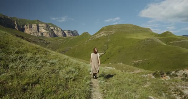 Rusland, Kaukasus. Een jonge vrouw loopt langs een pad tussen de heuvels — Stockvideo