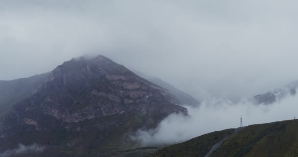 Klippiga bergstoppar täckta med moln i skymningen — Stockvideo
