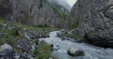 Dağ nehri, kayaların arasında güçlü bir akıntıyla kaynıyor.