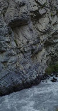 Dağ nehri, kayaların arasında güçlü bir akıntıyla kaynıyor.