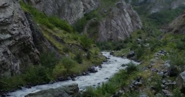 Dağ nehri, kayaların arasında güçlü bir akıntıyla kaynıyor.