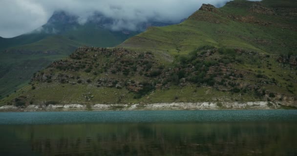 Una vista del lago de montaña al pie de las colinas vegetadas — Vídeo de stock