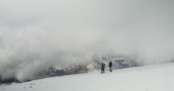 Rosja, Elbrus. Wspinacze schodzą z pokrytego śniegiem skalnego zbocza — Wideo stockowe