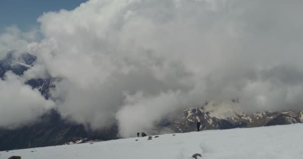 Rosja, Elbrus. Wspinacze schodzą z pokrytego śniegiem skalnego zbocza — Wideo stockowe