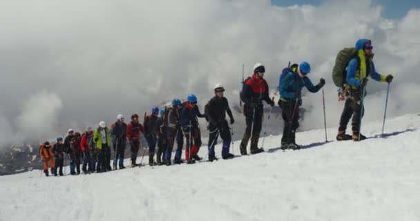 Rússia, Elbrus. Os escaladores sobem ao longo de uma encosta rochosa coberta de neve — Vídeo de Stock