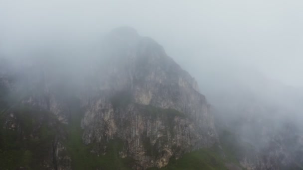 มุมมองของภูเขาหินสูงชันผ่านผ้าคลุมของเมฆจาก Quadcopter — วีดีโอสต็อก