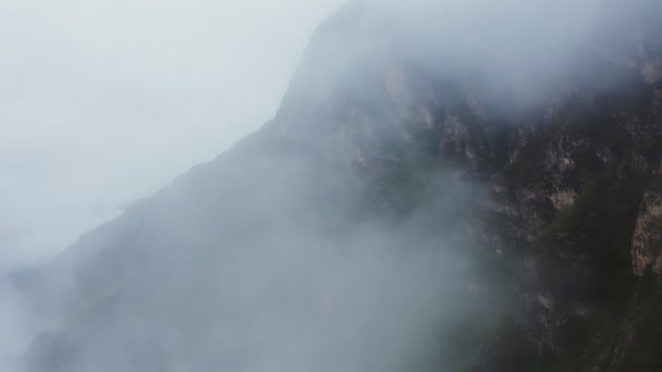 쿼드 로터에서 구름으로 덮인 베일을 통해 가파른 바위 산들을 바라본 모습 — 비디오