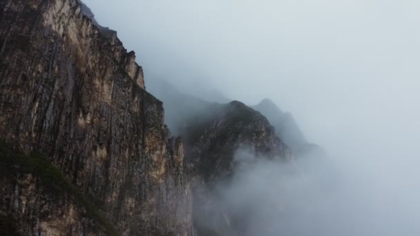 มุมมองของภูเขาหินสูงชันผ่านผ้าคลุมของเมฆจาก Quadcopter — วีดีโอสต็อก