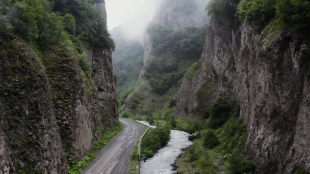 El Cáucaso. Un camino de montaña y un río en las tierras bajas entre montañas rocosas — Vídeo de stock