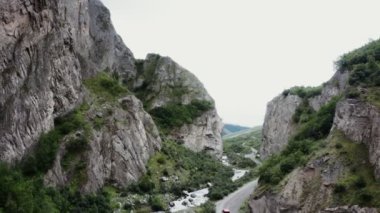 Taşlı bir dağ vadisi manzarası. Dağ nehri ve yol hareketli bir arabayla