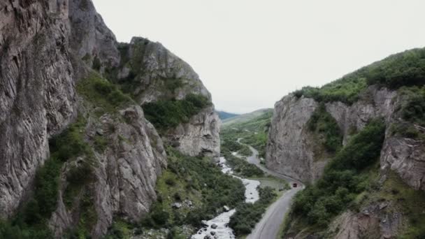Vista de un valle montañoso con rocas. Río de montaña y carretera con un coche en movimiento — Vídeo de stock