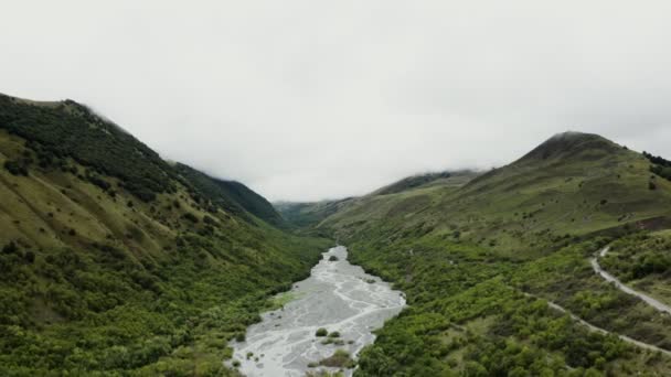 Река течет в низменности между зелеными холмами — стоковое видео