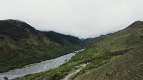 Річка тече в низинах між зеленими пагорбами — стокове відео