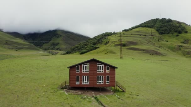 Una casa in legno solitario su palafitte in campo in una valle di montagna tra verdi colline — Video Stock