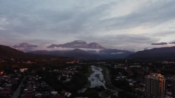 Een stad met huisje en hoogbouw aan de voet van de rotsachtige bergen — Stockvideo