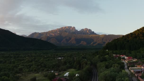 바위투성이 의산 기슭의 숲으로 뒤덮인 언덕 들 사이의 저지대에 있는 마을 — 비디오