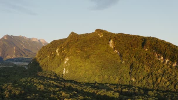 高くそびえる太陽の光の下で森に覆われた，岩の多い丘。 — ストック動画