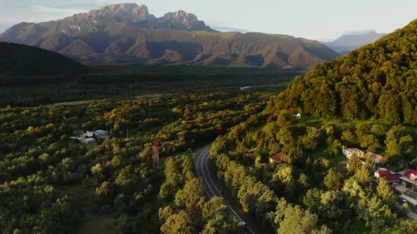 Uma cidade em planície entre colinas coberta com floresta a pé de montanhas rochosas — Vídeo de Stock