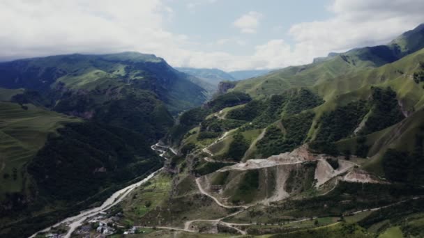 A town in lowland among hills covered with forest at foot of rocky mountains — Stock Video