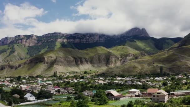 Uma cidade em planície entre colinas coberta com floresta a pé de montanhas rochosas — Vídeo de Stock