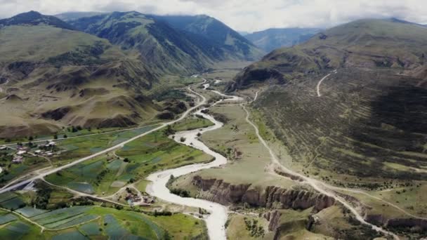 Una fattoria con campi coltivati e un fiume nella pianura di una valle di montagna. — Video Stock