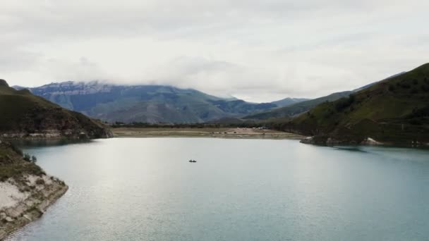 Ένας άντρας και μια γυναίκα ταξιδεύουν με μια βάρκα σε μια λίμνη ανάμεσα σε βραχώδη βουνά. — Αρχείο Βίντεο