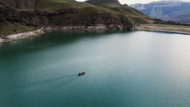 Mężczyzna i kobieta pływają łódką po jeziorze pośród skalistych gór. — Wideo stockowe