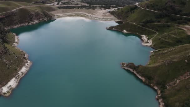 Widok na czyste górskie jezioro o nieregularnym kształcie położone pomiędzy zielonymi wzgórzami — Wideo stockowe