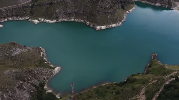 Una vista de claro lago de montaña de forma irregular situado entre verdes colinas — Vídeo de stock