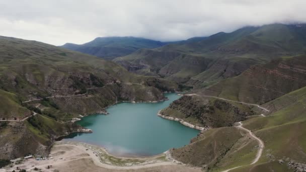 Una vista de claro lago de montaña de forma irregular situado entre verdes colinas — Vídeo de stock