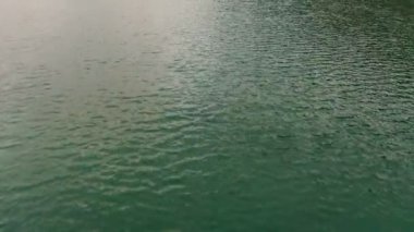 Drone suyun üzerinde uçuyor, su yüzeyinde küçük dalgalar.