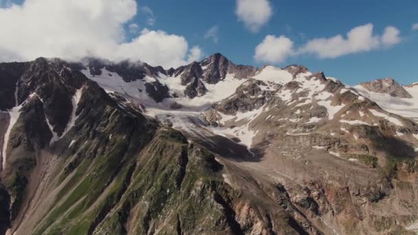 Απόκρημνα βραχώδη βουνά με γκρεμούς και καλάμια, καλυμμένα με χιόνι και σύννεφα — Αρχείο Βίντεο