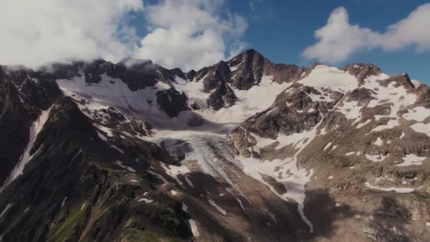 Montañas rocosas empinadas con acantilados y salientes, cubiertas de nieve y nubes — Vídeo de stock