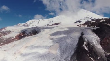 Uçurumları ve çıkıntıları olan dik kayalık dağlar, karlar ve bulutlarla kaplı.
