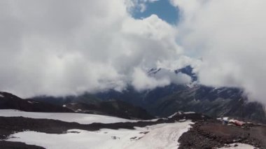 Elbrus Dağı 'nın karla kaplı zirvesi kalın bulutların arasından görünüyor.