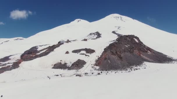 Zasněžený vrchol Mount Elbrus s mírnými svahy s běžeckými tratěmi a turisty — Stock video
