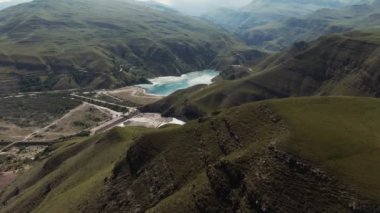 Yeşil tepeler arasında düzensiz şekilli berrak dağ gölü manzarası