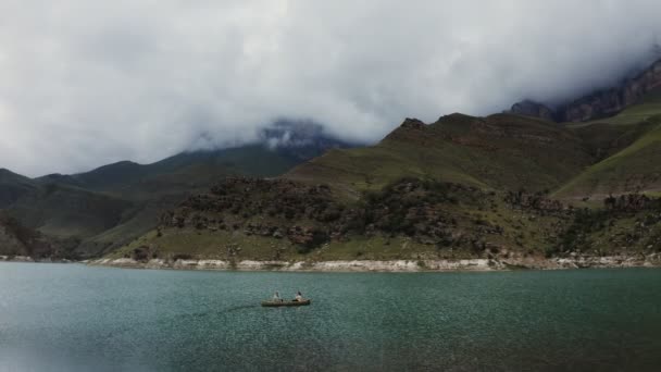 Seorang pria dan seorang wanita berlayar di perahu dayung di danau di antara pegunungan berbatu — Stok Video