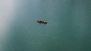 Genç bir adam ve bir kız gölde bir sandalla geziyorlar.