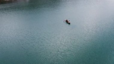 Genç bir adam ve bir kız gölde bir sandalla geziyorlar.