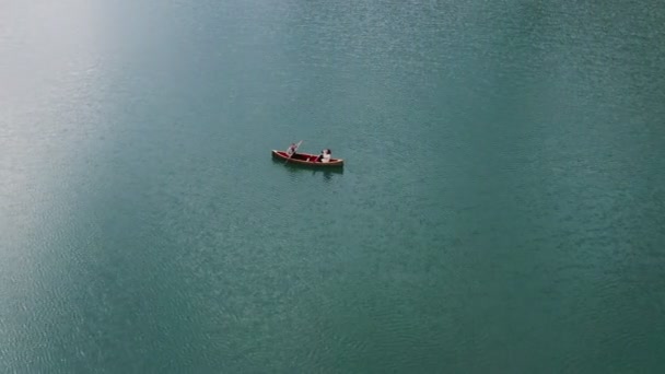 Een jonge man en een meisje varen op een roeiboot op het meer. — Stockvideo
