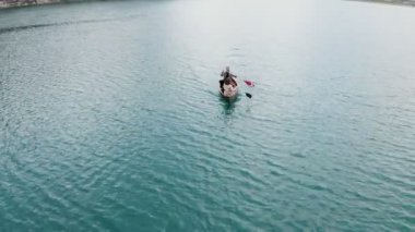 Genç bir adam ve bir kız gölde bir sandalla geziyorlar.